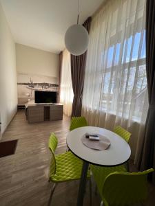 a living room with a table and green chairs at Apartamentai NIDA in Nida