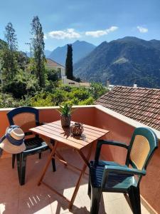 a wooden table and chairs on a balcony with mountains at Thea's country house in Aryiroúpolis