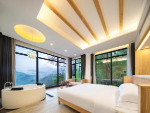 ein Schlafzimmer mit einer Badewanne, einem Bett und einem Bad in der Unterkunft Drunken Valley Manor - Zhangjiajie National Forest Park in Zhangjiajie