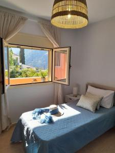 1 dormitorio con cama azul y ventana en Thea's country house, en Argyroupolis