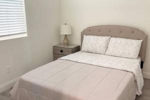 a white bedroom with a bed and a lamp on a night stand at Charming 3B3B Townhome (Relax & Family Friendly) in Pasadena