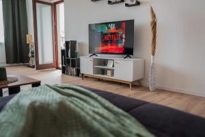 Südstrand, Zentral, Balkon, Wifi, Fahrstuhl, Parken في فيلهلمسهافن: غرفة معيشة مع تلفزيون بشاشة مسطحة على خزانة بيضاء