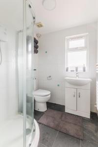 a white bathroom with a toilet and a sink at Surrey Stays - 4 bedroom house, sleeps 9, 2 bathrooms, CR5, near Gatwick Airport in Banstead