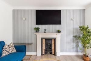 a living room with a fireplace with a tv above it at Surrey Stays - 4 bedroom house, sleeps 9, 2 bathrooms, CR5, near Gatwick Airport in Banstead