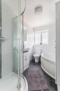 La salle de bains blanche est pourvue d'une baignoire, de toilettes et d'un lavabo. dans l'établissement Surrey Stays - 4 bedroom house, sleeps 9, 2 bathrooms, CR5, near Gatwick Airport, à Banstead