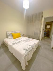 a bedroom with a large bed with a yellow pillow at L'Hermitage - Appartement T3 en bord de plage in Filaos