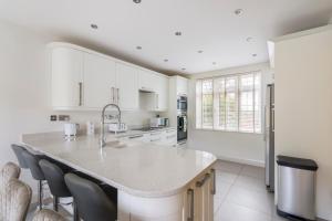 a kitchen with white cabinets and a large island at Surrey Stays - 5bed house, sleeps 12, CR5, near Gatwick Airport in Coulsdon