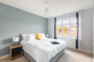 Un dormitorio con una gran cama blanca y una ventana en Surrey Stays - 5bed house, sleeps 12, CR5, near Gatwick Airport, en Coulsdon