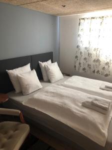 ein großes Bett mit weißen Kissen und einem Fenster in der Unterkunft Grenaa Bed and Breakfast in Grenå