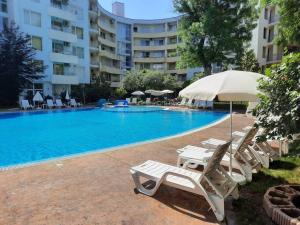 een zwembad met ligstoelen en een parasol naast een gebouw bij Central, 1 Bed Apt, 3* Yassen in Sunny Beach