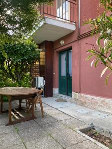 drewniany stół przed budynkiem z zielonymi drzwiami w obiekcie Apartment Fabiola w mieście Sistiana