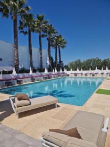 a swimming pool with lounge chairs and palm trees at Le Jardin de Babylone "r&eacute;serv&eacute; aux couples uniquement" in Cap d'Agde