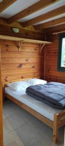 Bett in einem Zimmer mit einer Holzwand in der Unterkunft CAMPING ONLYCAMP LA ROSERAIE in Descartes