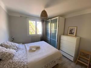 ein Schlafzimmer mit einem Bett, einer Kommode und einem Fenster in der Unterkunft Superbe appartement 2 chambres, clim, quartier calme entre la mer et les calanques in Marseille