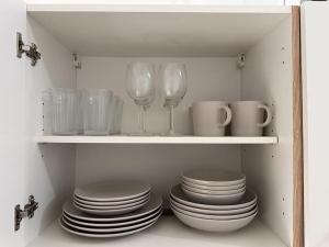 une étagère avec des assiettes, des verres à vin et des tasses dans l'établissement Design Apt. Messe•HBF•Uniklinik, à Essen