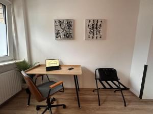 Design Apt. Messe•HBF•Uniklinik في إيسن: غرفة بها مكتب مع كرسيين وجهاز كمبيوتر محمول