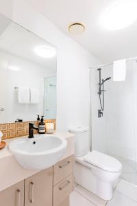 a white bathroom with a sink and a toilet at Kings Beach Surf Retreat - Beautiful Views in Caloundra