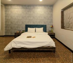 a bedroom with a large white bed with two tables at Backpacker Cowies in Mumbai