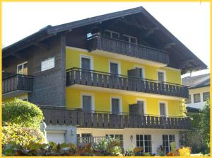 ein gelbes Gebäude mit Balkon darüber in der Unterkunft Ferienwohnungen Landhaus Gerum in St. Wolfgang