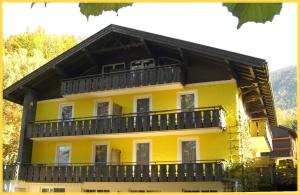 a yellow house with a balcony on top of it at Ferienwohnungen Landhaus Gerum in St. Wolfgang