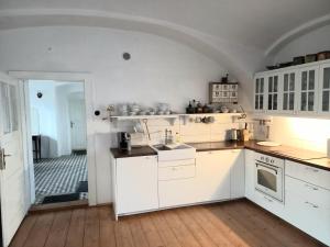 a kitchen with white cabinets and a wooden floor at Historic Farmhouse Kojetice in Kojetice