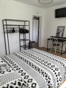 a bedroom with a bed with a black and white comforter at Au Grand Chêne Jolie T3 à 5 min d'Albi in Puygouzon