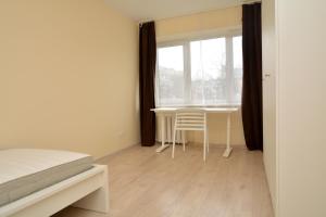 a bedroom with a bed and a table and a window at Vytauto av 9 - Kaunas Students Home LT in Kaunas