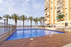 a swimming pool with palm trees and a building at Estudio Fetén Algarrobo Costa in Algarrobo-Costa