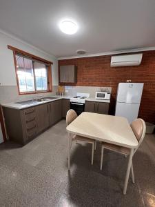 uma cozinha com uma mesa e um frigorífico branco em Greenways Holiday Units em Tocumwal