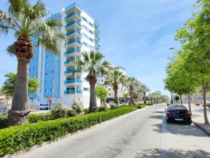 a street with palm trees and a building at Global Properties, Moderno apartamento a 3 minutos de la playa in Puerto de Sagunto