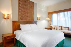 a hotel room with a large white bed and a chair at Hotel Sahid Jaya Lippo Cikarang in Cikarang