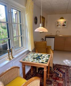 ein Wohnzimmer mit einem Tisch und Stühlen sowie eine Küche in der Unterkunft Anne Just's Havehotel in Blokhus
