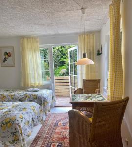 a bedroom with two beds and a table and a window at Anne Just's Havehotel in Blokhus