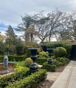 a garden with three black vases in the middle at Anne Just's Havehotel in Blokhus