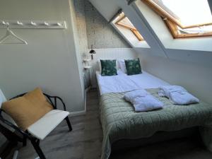 um quarto com uma cama e uma cadeira num sótão em Rörums Gårdshotell em Simrishamn