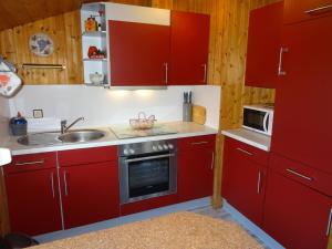 a kitchen with red cabinets and a sink at Ferienhäuser Hansen-Rerup in Silberstedt