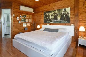 een slaapkamer met een wit bed in een houten muur bij Biktot Nofim in Manot