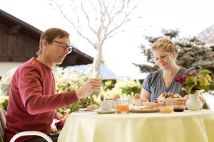 un hombre y una mujer sentados en una mesa comiendo comida en Pension Kleon, en Rifiano