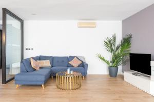 ein Wohnzimmer mit einem blauen Sofa und einem Fernseher in der Unterkunft Apartamento Moderno Calle Larios in Málaga