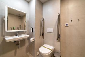 a bathroom with a sink and a toilet and a mirror at Alidreams Lola Center Apartamentos in Alicante