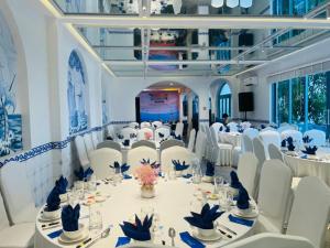 SUNTORINI BOUTIQUE HOTEL في فنغ تاو: قاعة احتفالات بكراسي بيضاء وطاولات في غرفة