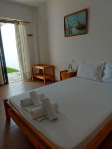 a bedroom with a large white bed with towels on it at PANSION ALEXANDROS BY THE SEA in Nea Skioni