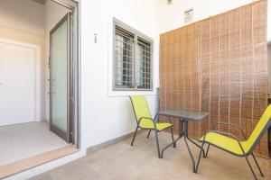 un patio con 2 sillas, una mesa y una ventana en Mare del Salento Residence by BarbarHouse, en Torre Lapillo