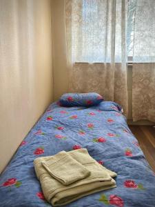 a bed with a blue comforter with flowers on it at Tilava huoneisto Keuruun keskustassa in Keuruu