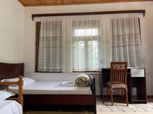 a bedroom with a bed and a window with a chair at Guest House Bakuli in Gjirokastër