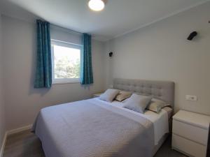 Schlafzimmer mit einem großen weißen Bett und einem Fenster in der Unterkunft Apartments Ivančić in Mimice