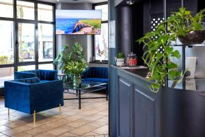 a lobby with blue chairs and a table with plants at Hotel Stadt Gütersloh in Gütersloh
