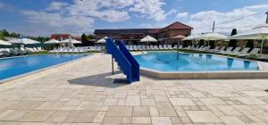 ein Schwimmbad mit blauer Rutsche in einem Ferienresort in der Unterkunft Motel LAGUNA in Beiuş