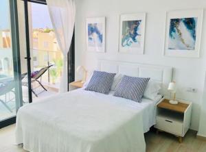 アリカンテにあるVillamartin Spacious Modern flat -3 pools jacuzzi tennis golfの白いベッドルーム(ベッド1台、バルコニー付)