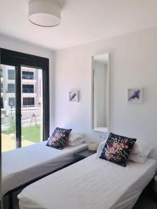 アリカンテにあるVillamartin Spacious Modern flat -3 pools jacuzzi tennis golfのベッド2台、鏡、窓が備わる客室です。